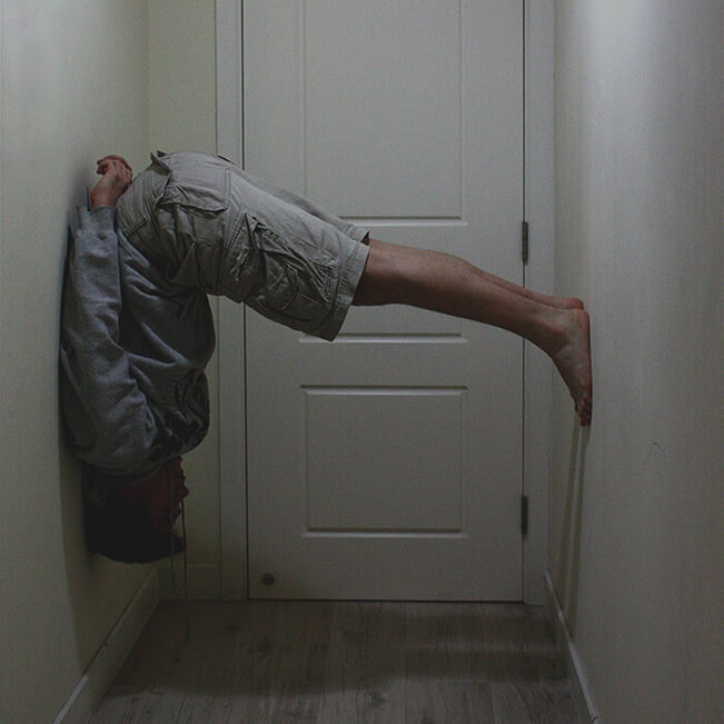 Photo of graphic and web designer Charlie wedged upside-down between two walls